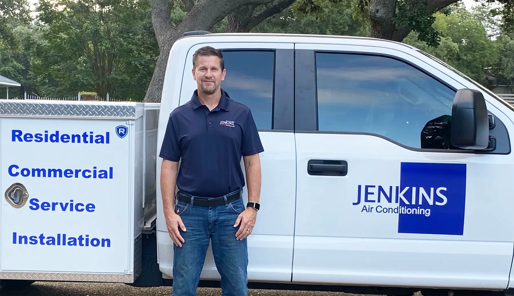 Brandon Jenkins, owner of Jenkins Air Conditioning, standing in front of a branded service truck